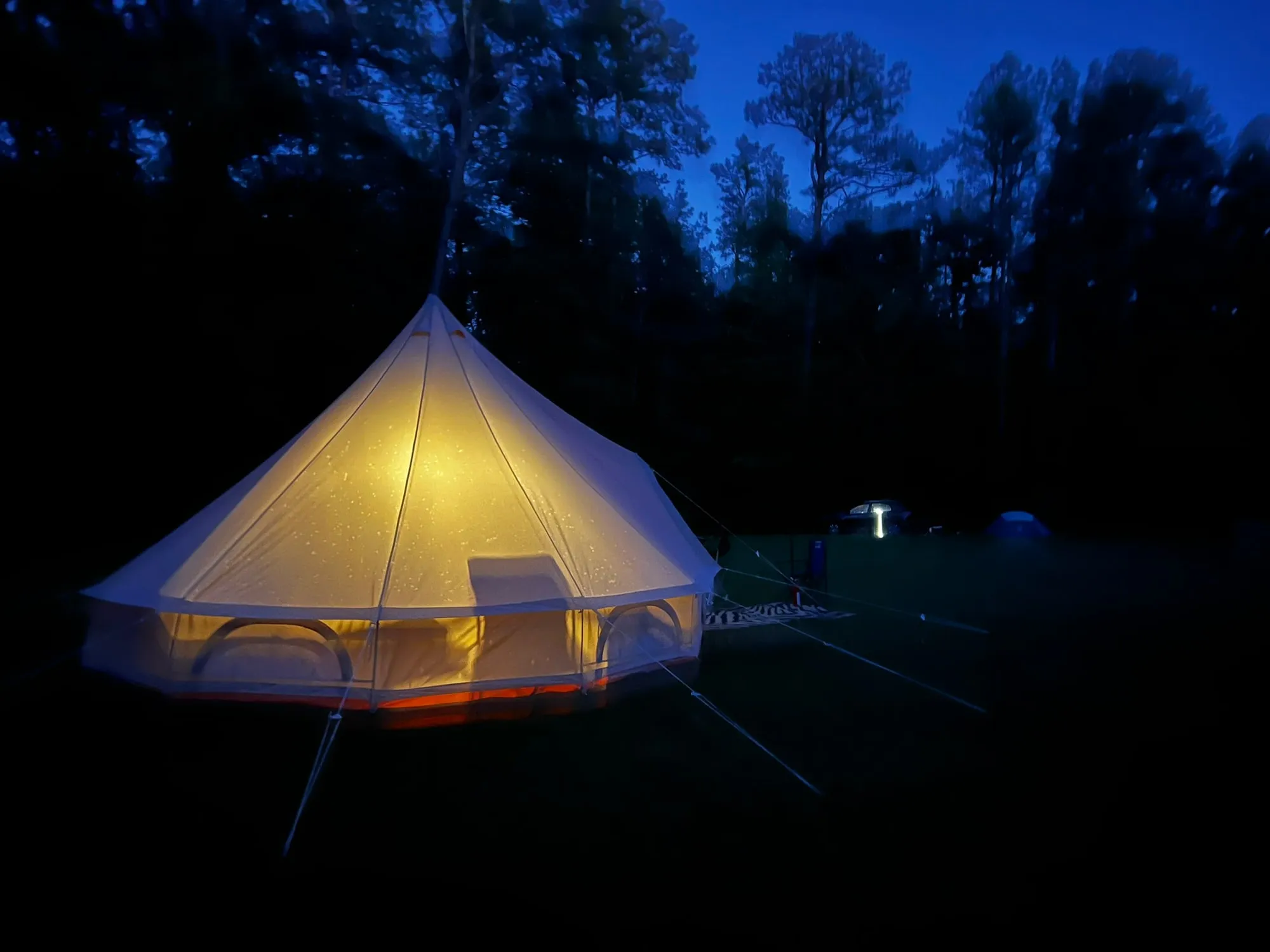 A lit canvas tent at a campsite at dusk