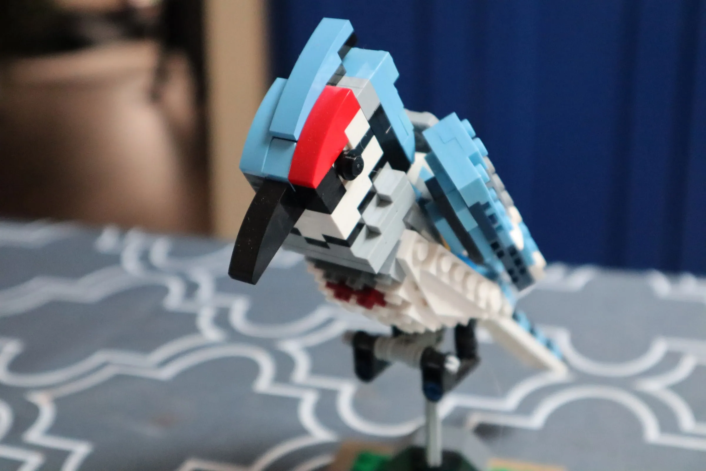Photograph of a small block-built bird on a patterned surface, used as a composition reference
