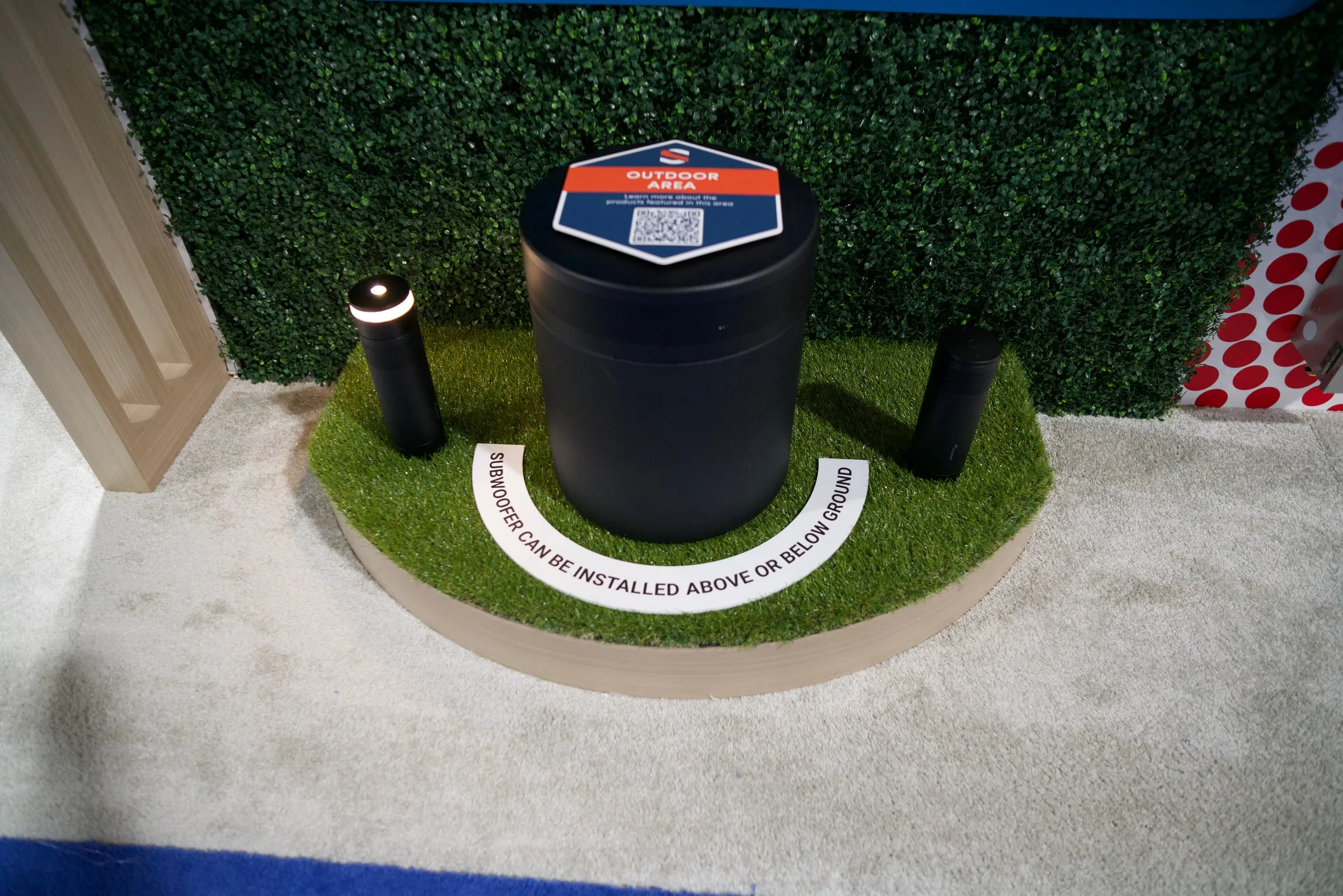 Episode outdoor speaker on a raised turf platform with an award sign