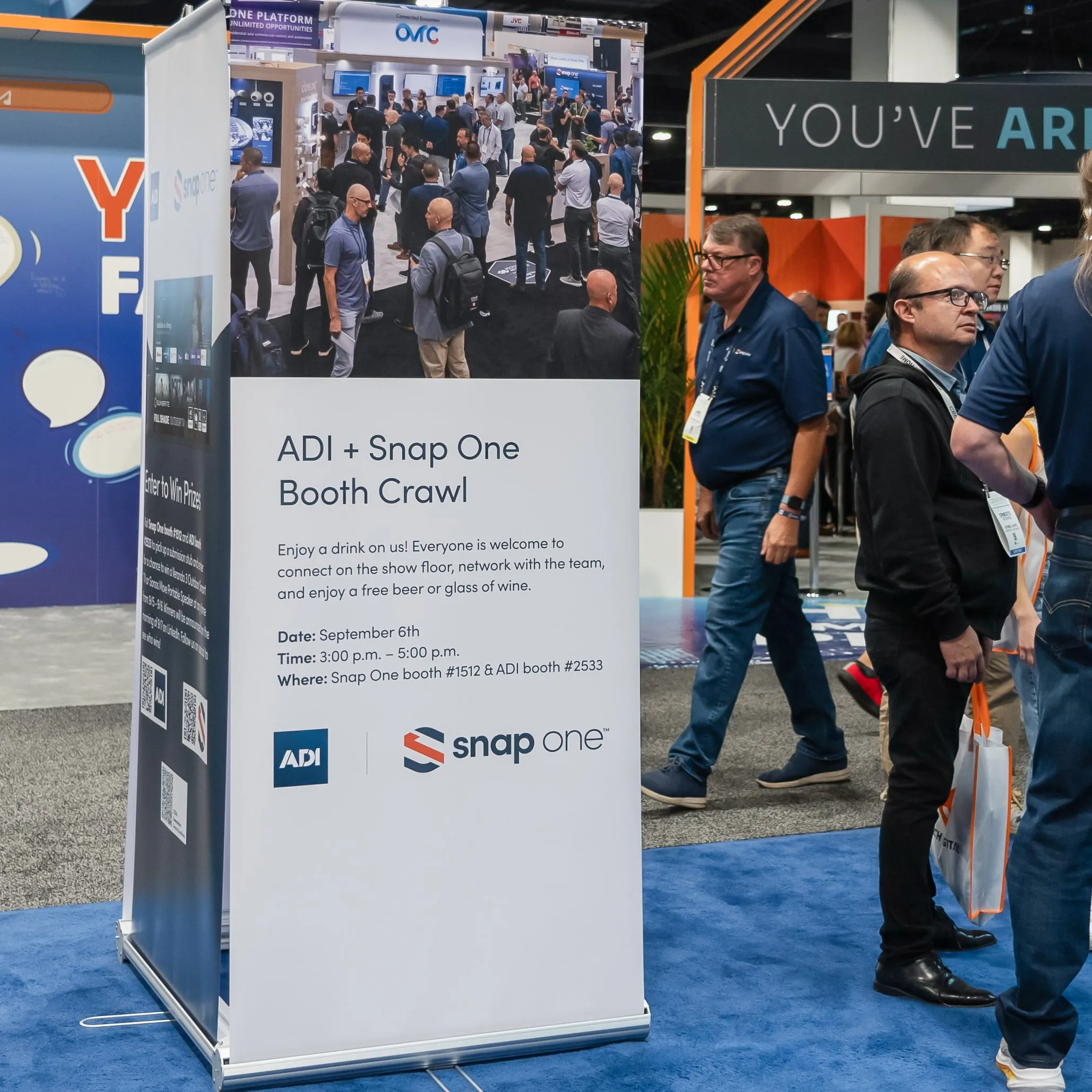 ADI and Snap One booth crawl sign beside a busy aisle