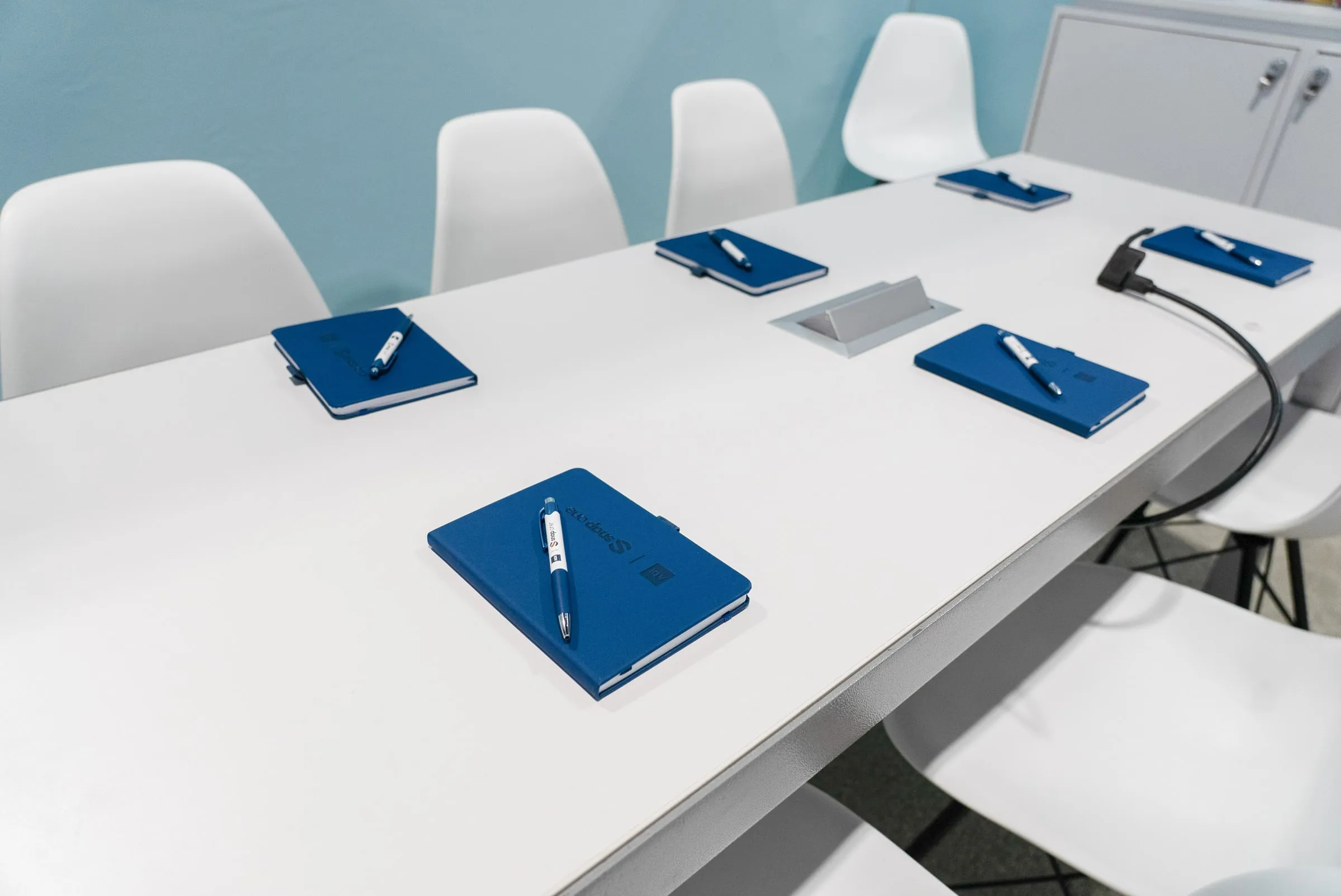 Meeting table set with Snap One notebooks and pens