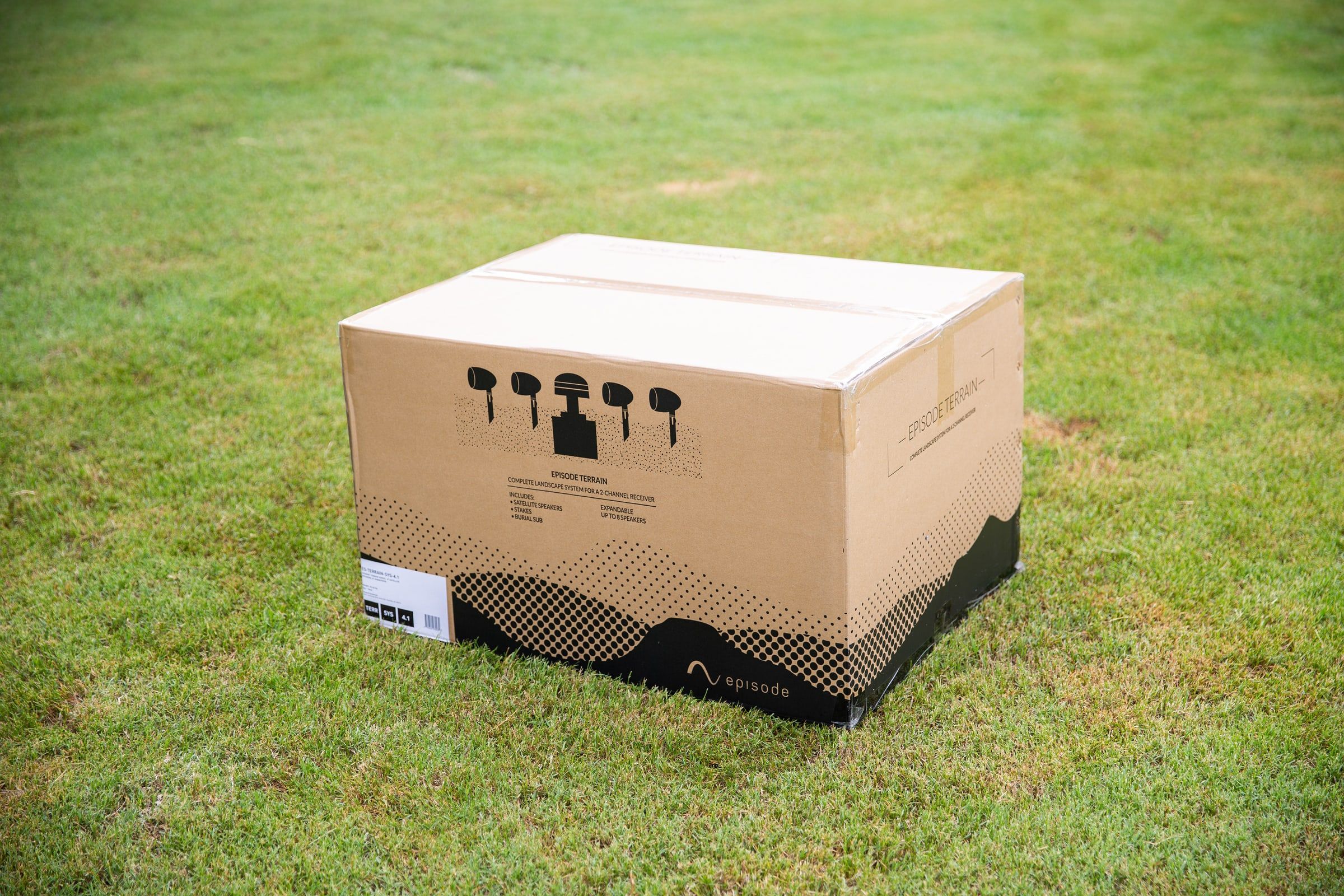 Episode Terrain subwoofer box on grass with product line drawings on top