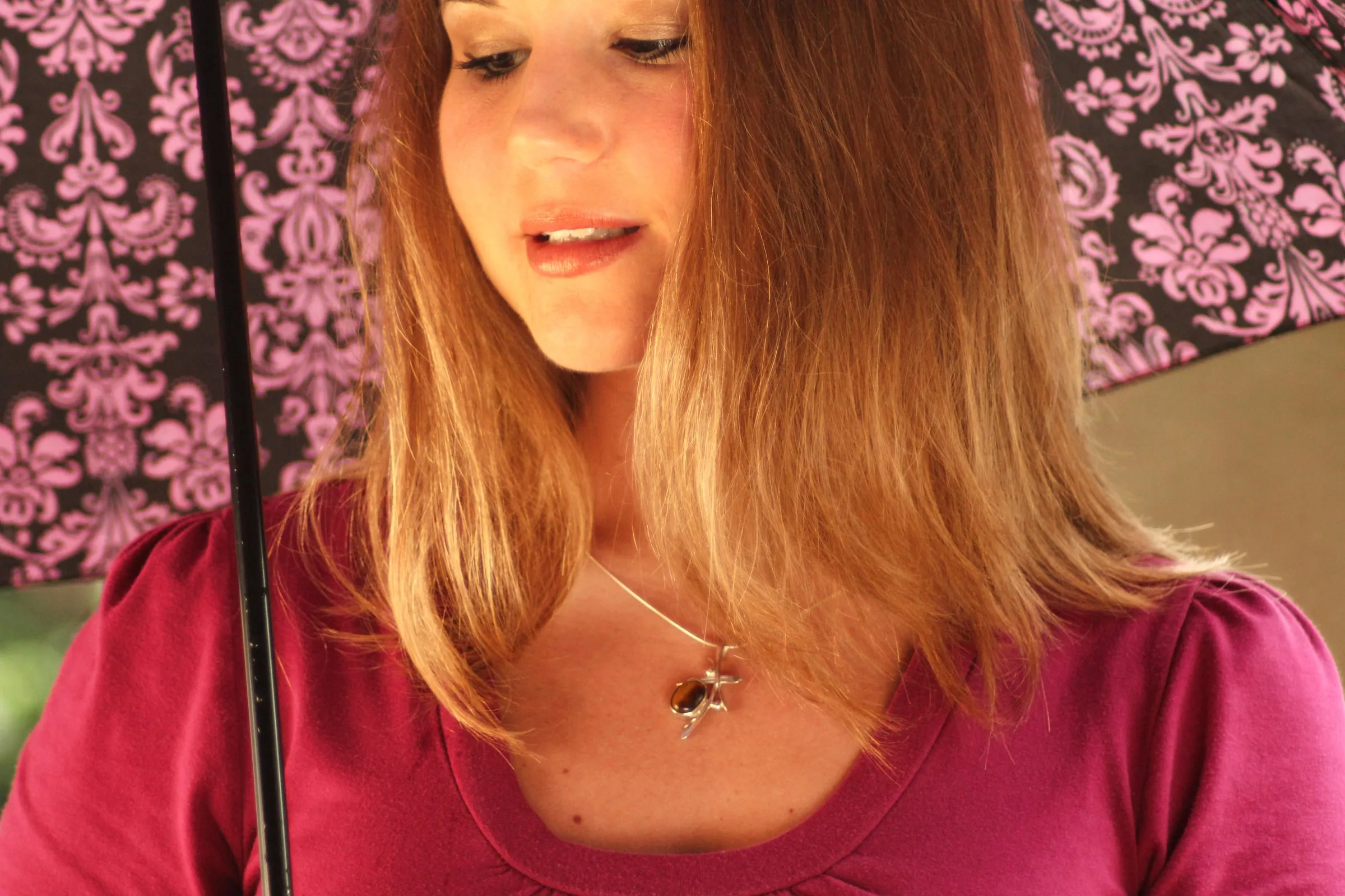 Model looking down under the umbrella, showing the necklace