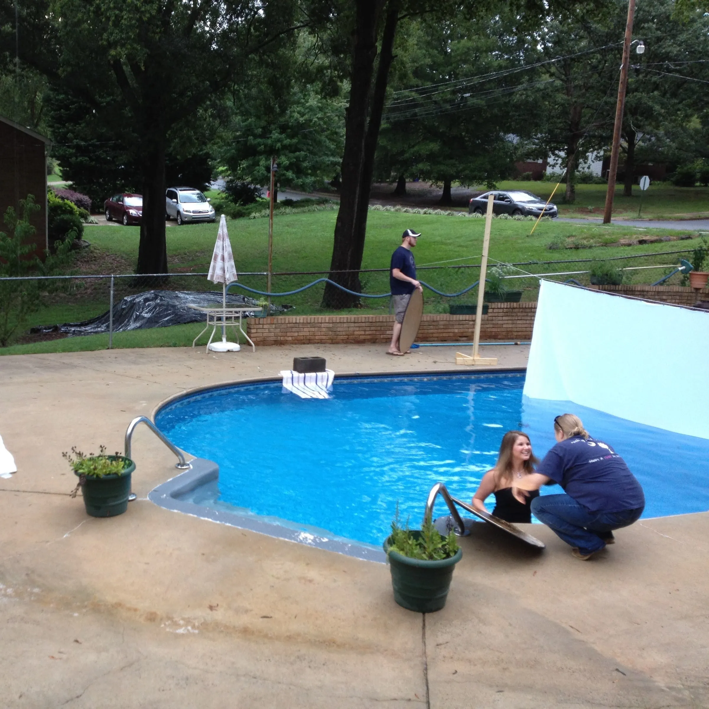 Behind the scenes: photographer and model set up beside a backyard pool with a white backdrop