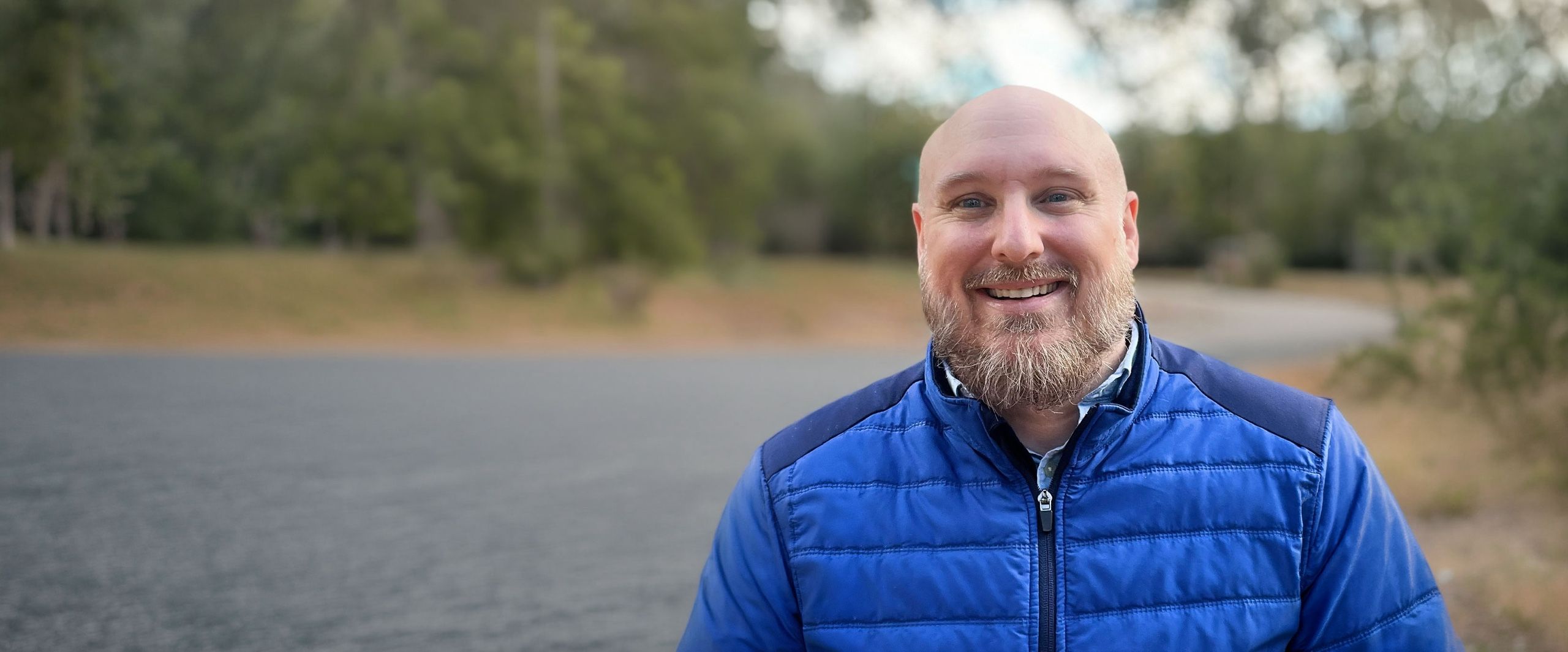 David Hennes smiling outdoors in a blue jacket