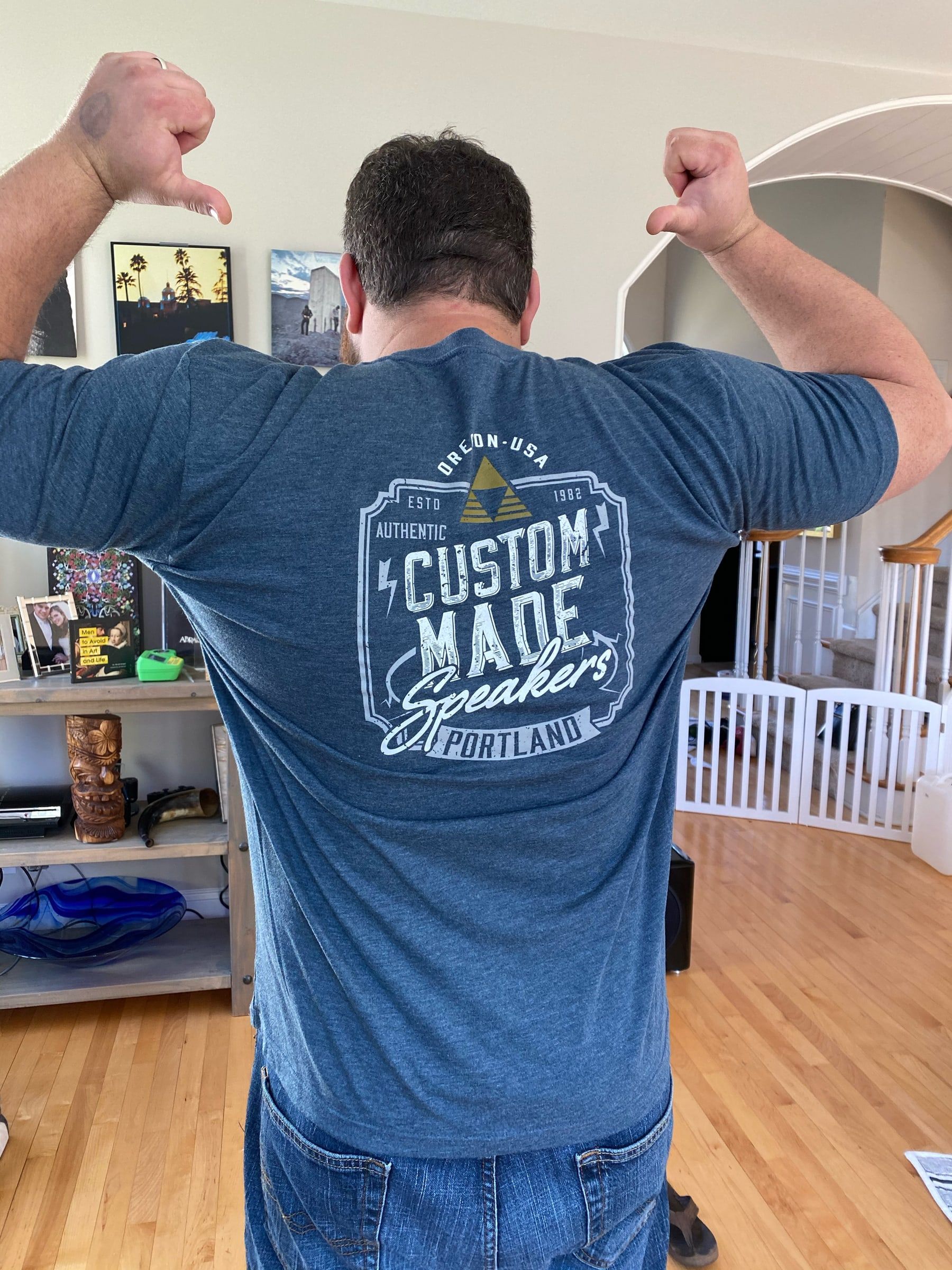 Man showing the back of a blue "Custom Made" Snap One T-shirt